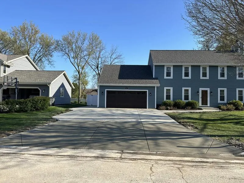 Completed concrete driveway at same blue colonial home, blue sky