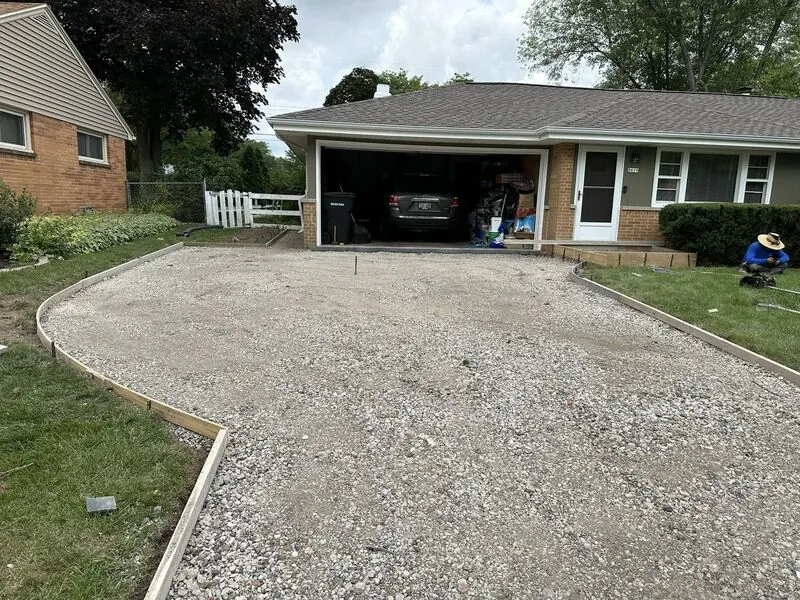 Gravel sub-base with wooden forms ready for concrete pour at same brick ranch